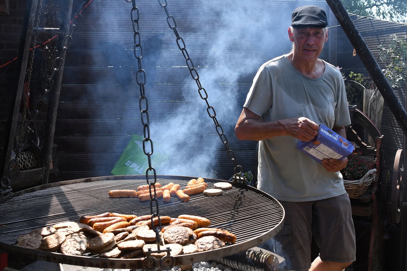 Worsten en burgers op de grote vuurschaal-BBQ