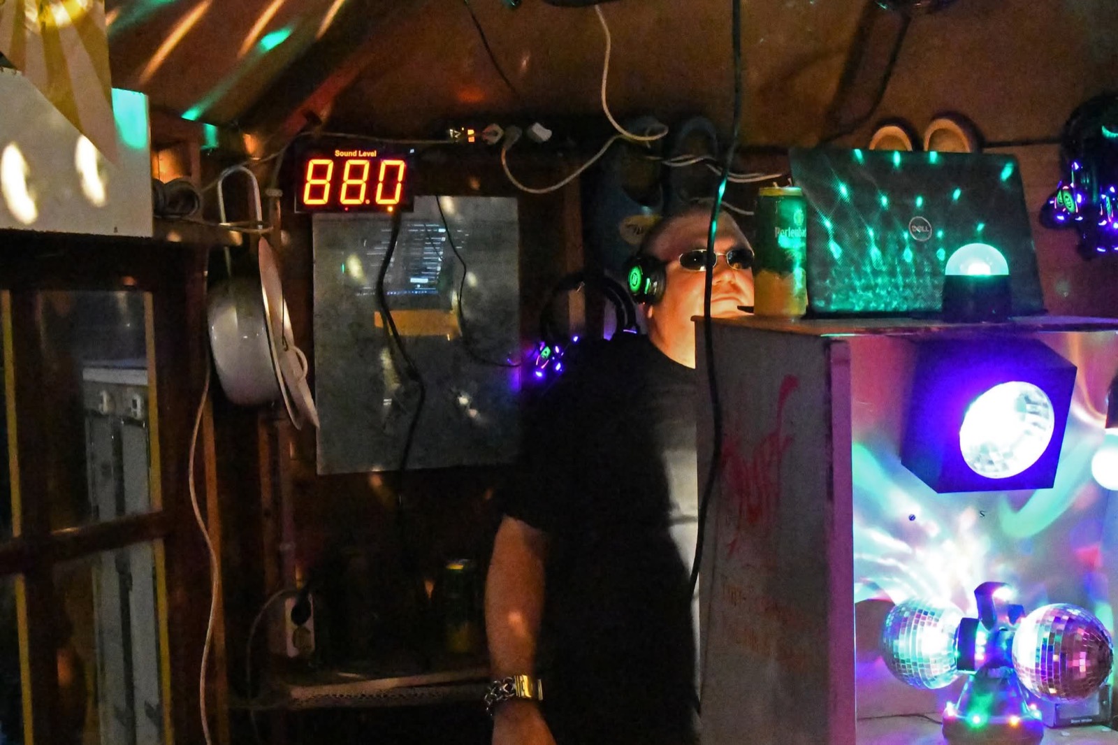 DJ Der Theo met koptelefoon tussen de discolampen van de silent disco